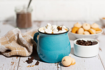 hot chocolate with marshmallows in a mug and cookies on a white table