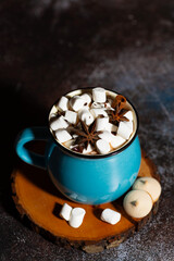 hot chocolate with spices and marshmallows on a dark table, vertical