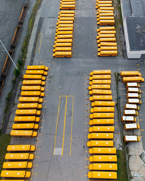 Top down view of rows of school buses in open garage storage yard in Michigan.