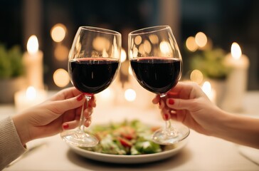 Obraz premium Hands of a couple toasting with glasses of red wine at a candlelit table with bokeh lights, celebrating romance