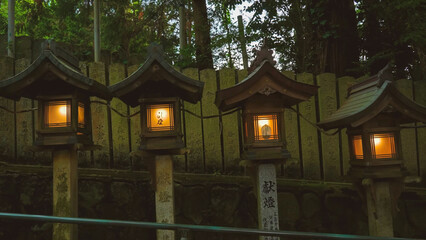: A row of traditional Japanese stone lanterns with glowing warm lights and teal roofs