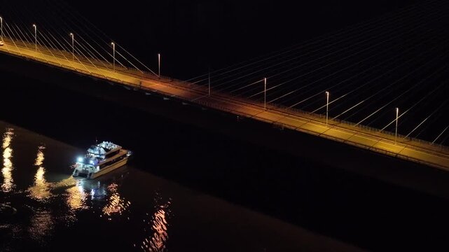 Aerial night shot showing cars crossing San Roque Gonz&aacute;lez Bridge and a boat below.