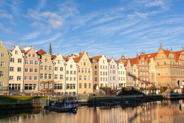 Naklejka premium The waterfront in Gdansk, Poland. Buildings and the river under bright skies. Green Gate in the background