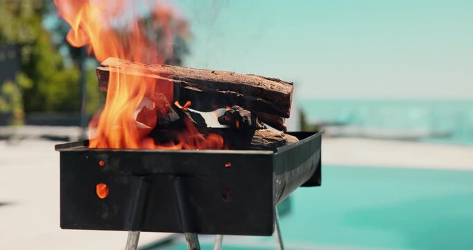 Empty, pool and bbq with fire in backyard for party, holiday and lunch on weekend outdoor. Cookout, barbecue and grill with flame, wood and heat for social gathering, celebration and vacation