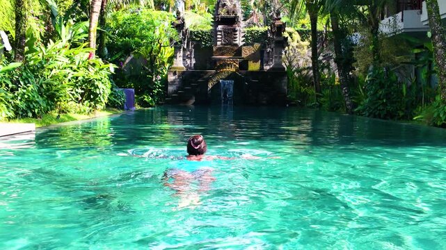 Relaxing swim in serene Bali pool, lush greenery, calm vibe, slow motion
