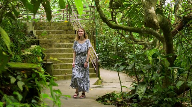 Female traveler in flowing summer dress explores lush green Ubud monkey forest