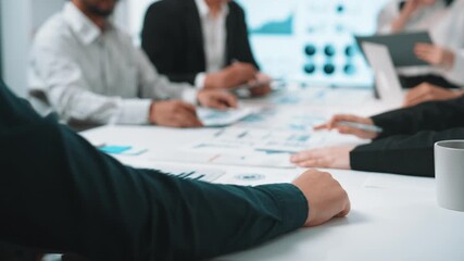 A diverse team engages in an active business discussion, analyzing charts and data on laptops, emphasizing collaboration and strategy in a professional atmosphere. SACTR - Powered by Adobe