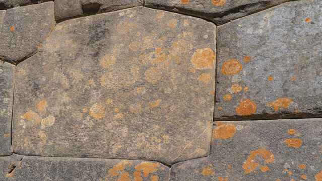 Unique polygonal ashlar masonry. Ancient Inca architecture. The boulders are smoothly hewn, closely fitted. Orange lichens on the surface. Close-up. The texture. Peru. Cusco. Ollantaytambo 