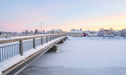 Obraz premium Snowy Bridge Over Frozen River in Winter Town
