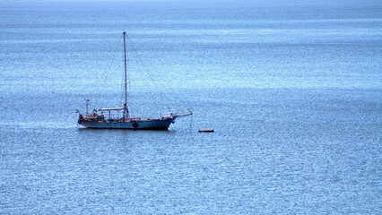 An old yacht in the open sea at anchor on a summer day