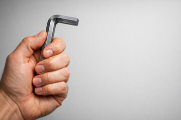 Male hand gripping a silver allen key tool isolated.