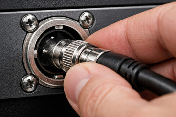 Detailed view of BNC connector being plugged into SDI port of digital cinema camera.