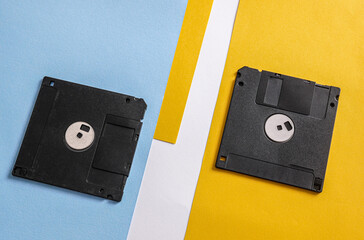 Two black 3.5 inch floppy disks on colored background