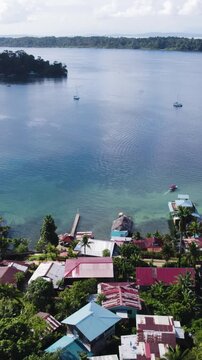 Vertical aerial pull back and rising shot showcasing colorful houses along the bay of Bastimentos Island in Panama&rsquo;s Bocas del Toro District.