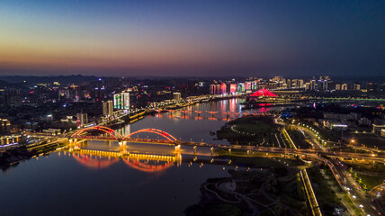 Naklejka premium Nanchong Night Aerial View with Illuminated Bridge and River Reflection