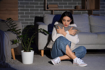Scared young woman with pillow in dark room