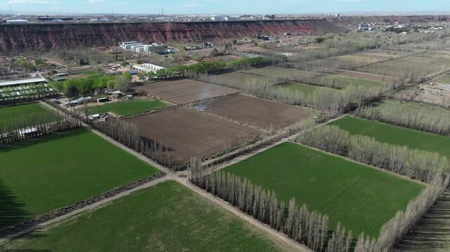 A drone pans across the low-lying green fields of A&ntilde;elo.In the background,the plateau with its oil extraction activity is visible.Far in the distance, the Auca Mahuida volcano can be seen.Vaca Muerta.