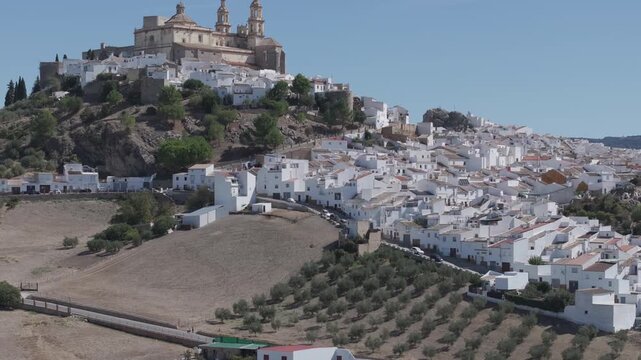Aerial drone shot panorama wide view of the white town village of Olvera in Andalusia, Spain, Europe. Traditional castle and church on hill, and olive trees