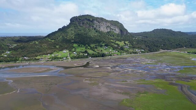 Hualaihue, Chile: Aerial view of coastal area Hualaihue, commune in Lake district near Hornopiren in the green patagonia of Chile with mountain in the background on sunny day. Taken with forward motio