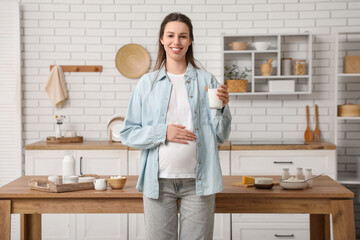 Young pregnant woman with different dairy products on table in kitchen
