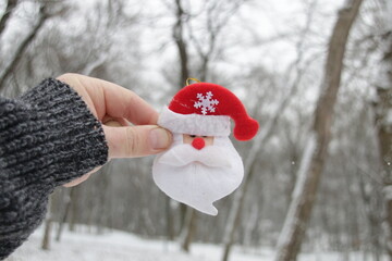 Hand holds santa claus on the background of the winter forest. Christmas background.