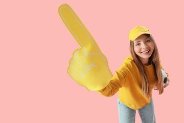 Female soccer fan with foam hand and ball on pink background
