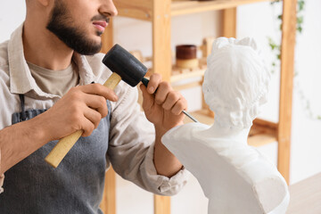 Male sculptor carving bust in workshop, closeup