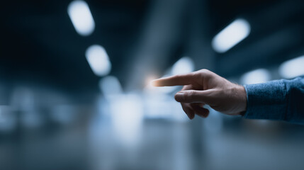 An individual hand, illuminated, extends forward, its index finger pointing with precision in a futuristic, modern environment.