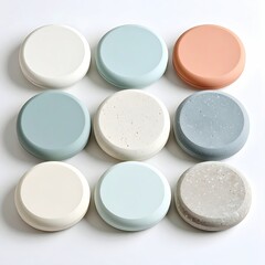 Nine round, smooth, colorful coasters arranged in a grid.  Soft pastel shades of cream, light blue, and peach. Some speckled with tiny flecks of another color
