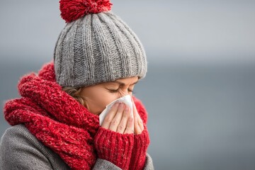 Woman in Knit Hat and Scarf Sneezing Outdoors on a Chilly Day