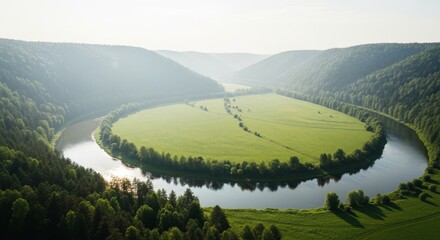 Meandering river through lush green valley with distant hazy mountains
