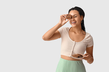 Young African-American woman with chocolate cookies on white background