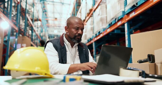 Laptop, logistics and typing with man at desk in warehouse for distribution or shipping update. Computer, management and supply chain with mature person in storage depot for agenda or schedule