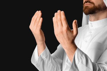 Muslim man praying on black background, closeup. Ramadan celebration