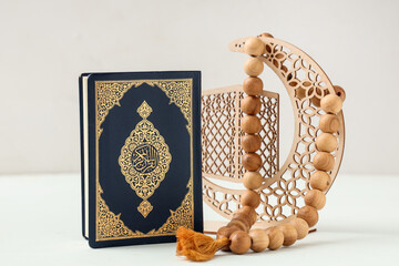 Koran, decorative crescent and prayer beads for Ramadan on white background
