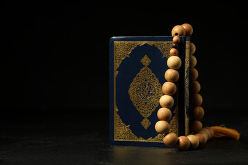 Koran and prayer beads for Ramadan on black grunge background © Pixel-Shot