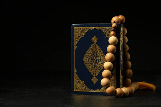 Koran and prayer beads for Ramadan on black grunge background