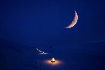 Peaceful winter night with glowing lanterns under crescent moon