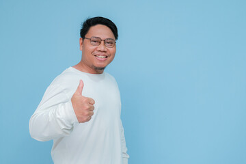 a young asian man raises his thumb with happy facial expression for his success 