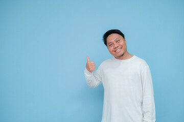 a young asian man raises his thumb with happy facial expression for his success 