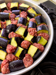 Raw eggplant and minced meat cubes arranged for a traditional casserole
