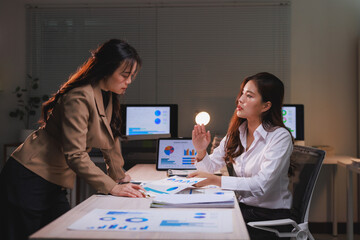 Businesswomen discussing data reports in a dark office