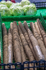 Long brown burdock roots or gobo stacked in a crate at an organic vegetable stall. Traditional Asian root crop for healthy nutrition, detox and natural medicine