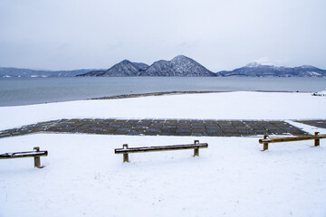 The calm surface of the lake covered with snowy fields and the shadow of the mountains of Nakajima