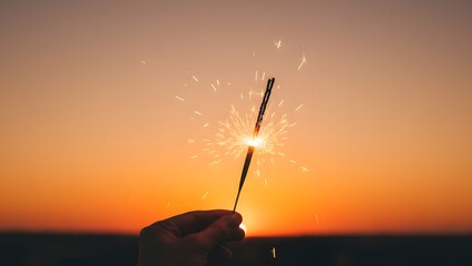 Hand Holding Sparkler at Vibrant Sunset.