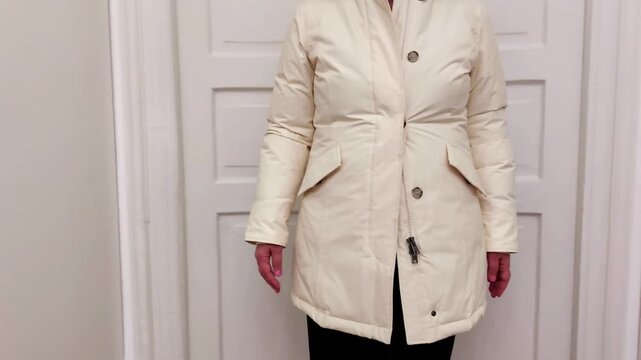 A cream padded parka jacket shown in a winter try on, highlighting its warm insulation, soft hood trim, and clean seasonal style. A simple, cozy look focused on fit and texture