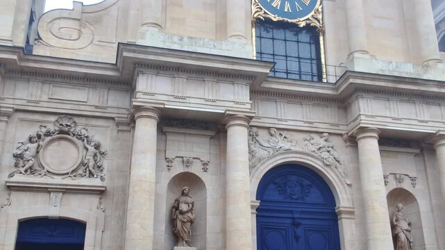 Neoclassical facade of Notre-Dame de Versailles church. Features a prominent blue clock with gold numerals. Historic religious architecture in France