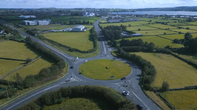 Drone footage of the Lake View Roundabout in Midleton, Ireland, connecting the N25 and R630 surrounded by green fields and a scenic lake background.