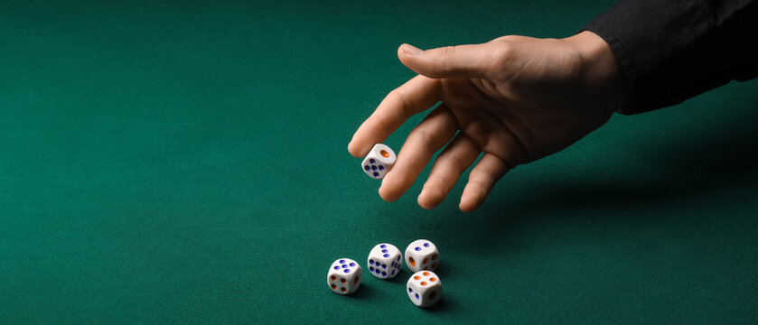 Hand throwing game dices on green background with space for text