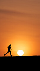 Silhouette of a person running against a bright sunset backdrop
